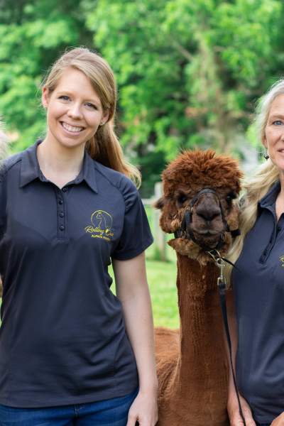 Two Woman holding to alpacas