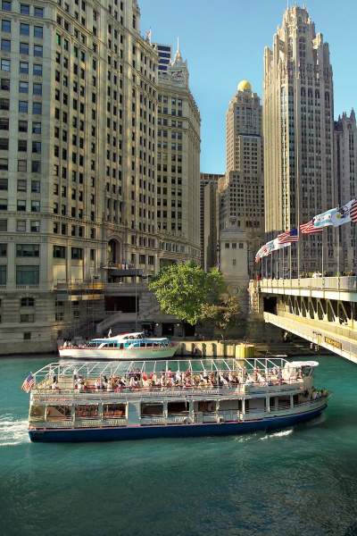An architecture river tour boat passes under a bridge in Chicago