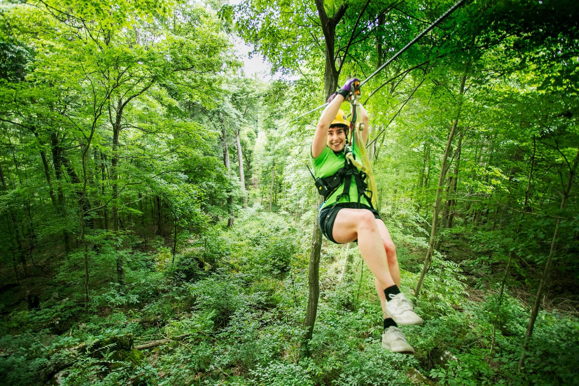 A woman sliding down a line from a flying fox amongst the trees