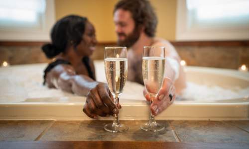 Couple having champagne in the bath tub. 