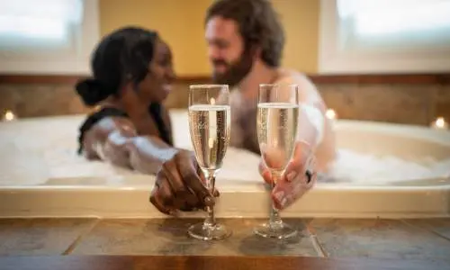 Couple having champagne in the bath tub. 