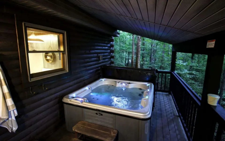 A hot tub sitting on the deck on a cabin in the woods