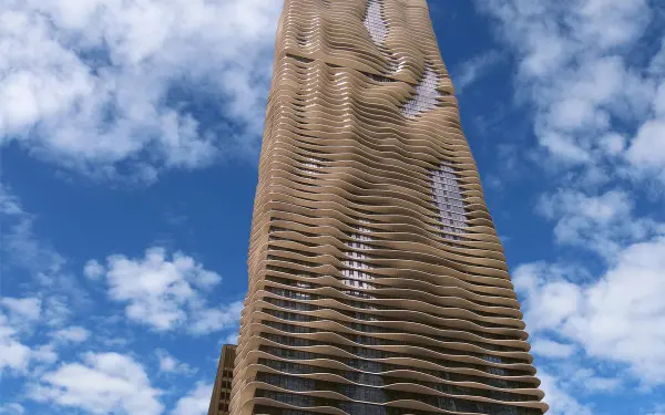 The exterior of the Aqua Tower in Chicago, against a cloud-filled blue sky.