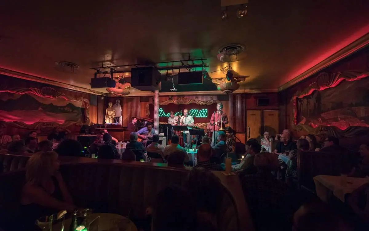A band plays in a dimly lit room in the green mill speakeasy