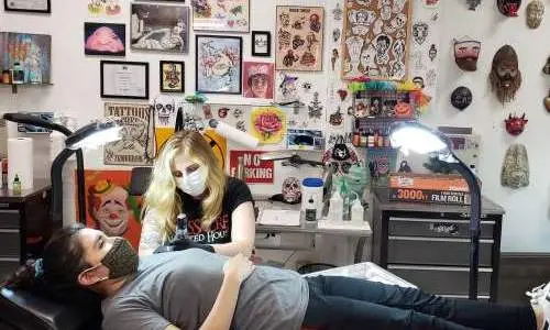 Lady laying down on a chair and getting tattooed by a tattoo artist.