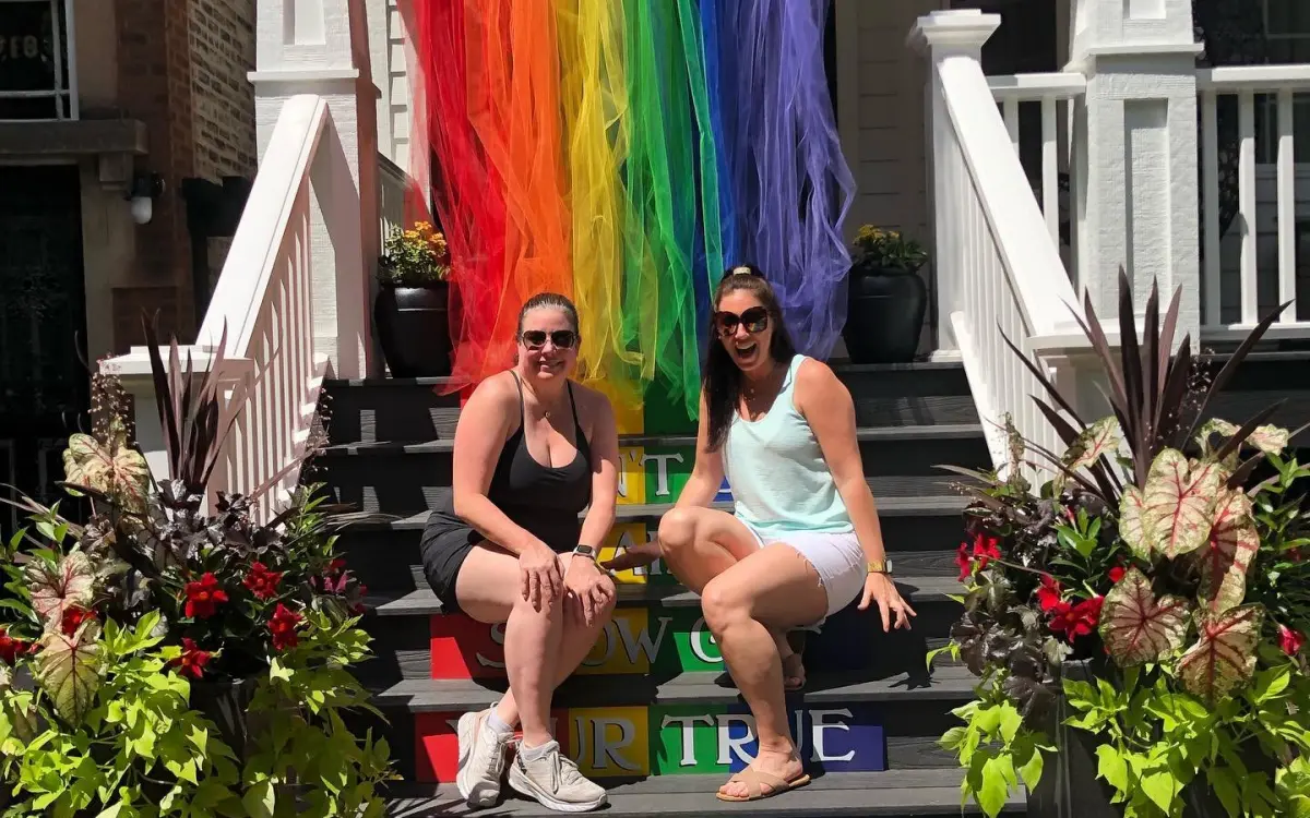 Girls standing in front of pride flag.