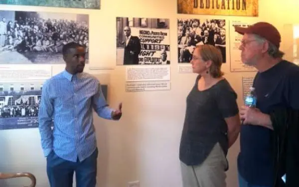 A guide talking to visitors about an exhibition they are standing infront of. 