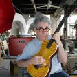 Ian Schneller strumming a guitar that he made.