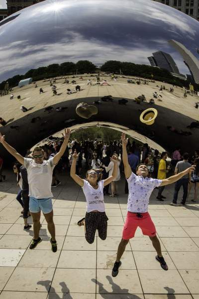 Three people jumping up in the air in front of The Bean landmark in Chicago