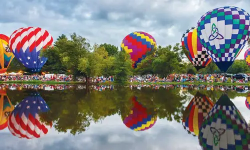 Hot air balloons surround a lake (Photo Don Burkett)
