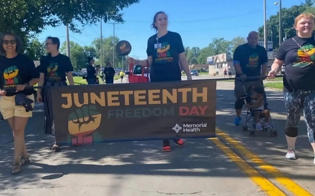 A group of parade attendees walk with a sign in Springfield