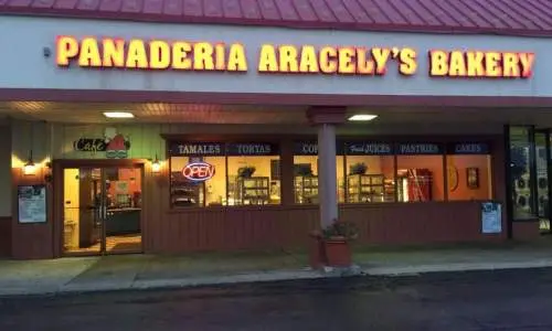 Exterior of Panaderia Aracey's Bakery with its sign lit.