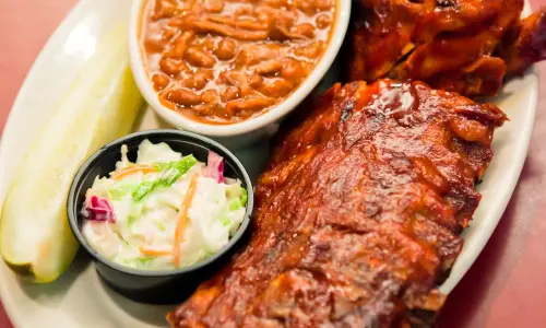 A plate of bbq food including ribs, slaw and beans