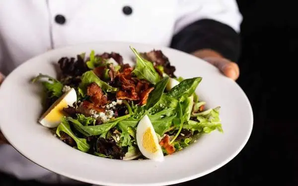 A plate with a caesar salad being held by a chef