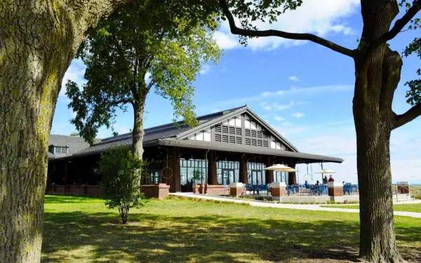 The exterior of a lakeside restaurant with trees in the foreground 