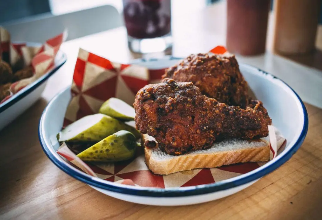 Two chicken drumsticks and pickles on a piece of bread