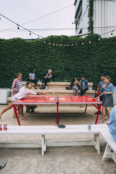 Patrons drinking beers and playing table tennis in the outdoors