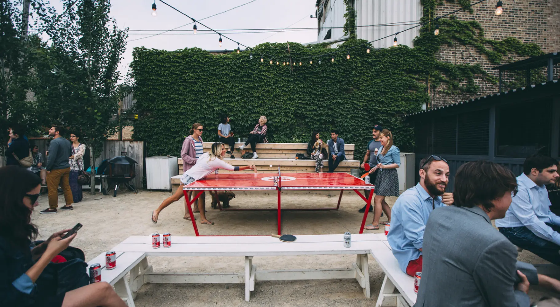 Patrons drinking beers and playing table tennis in the outdoors