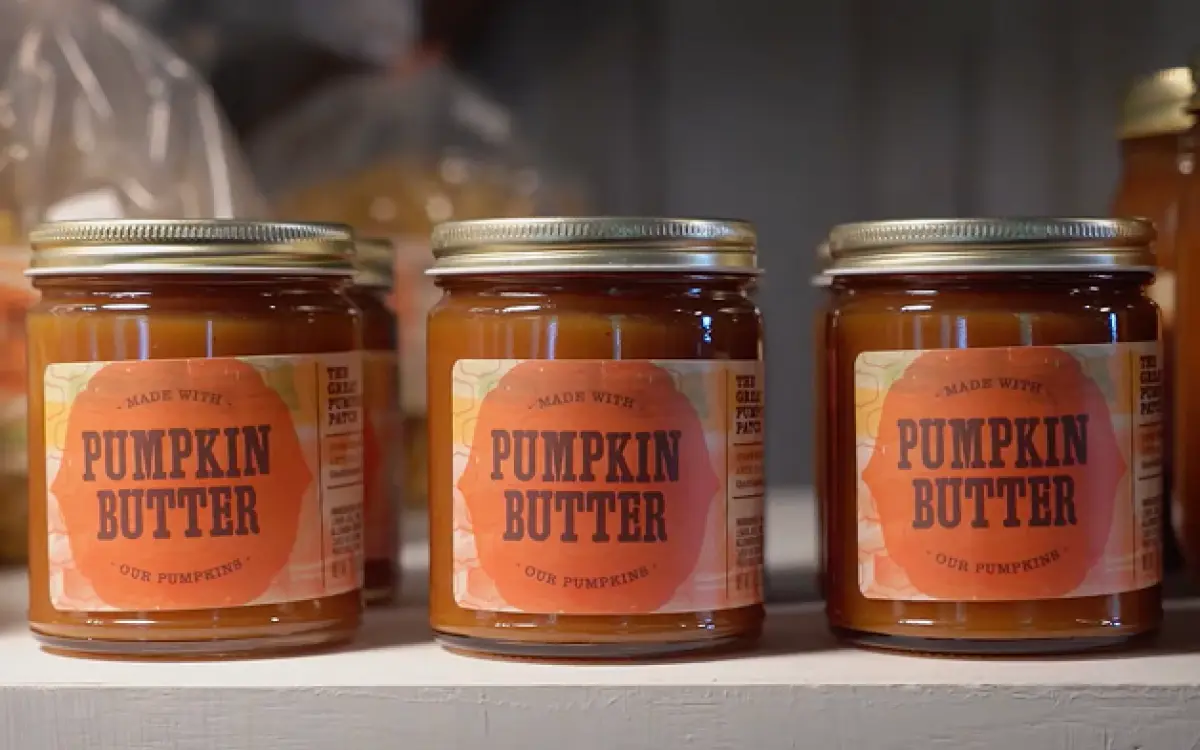 Three glass jars labeled "Pumpkin Butter" lined up on a shelf. 