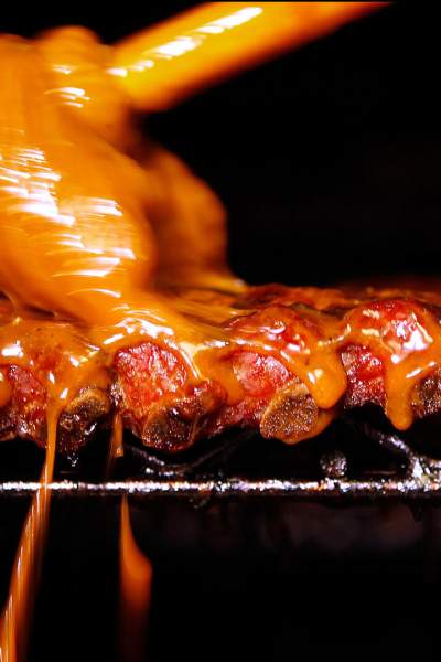 A rack of ribs with sauce being poured overtop