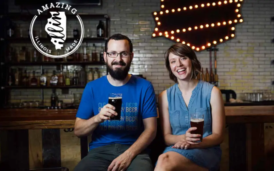 A couple holding up a pint of beer.