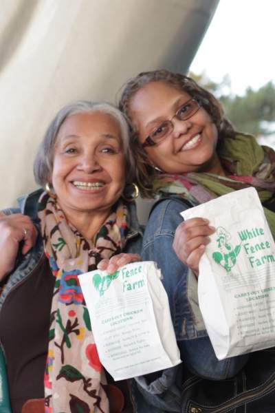 Two women holding bags of White Fence Farm fried chicken