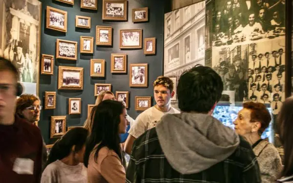 Museum visitors gathered in a small room which is covered by photographs