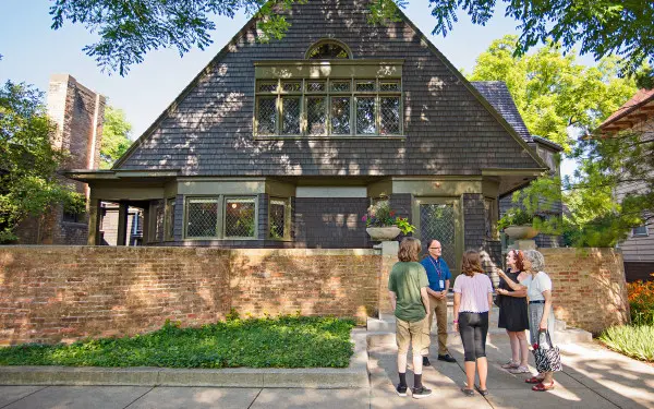 A guide speaks to a tour group on the sidewalk in front of Frank Lloyd Wright's house and studio in Oak Park