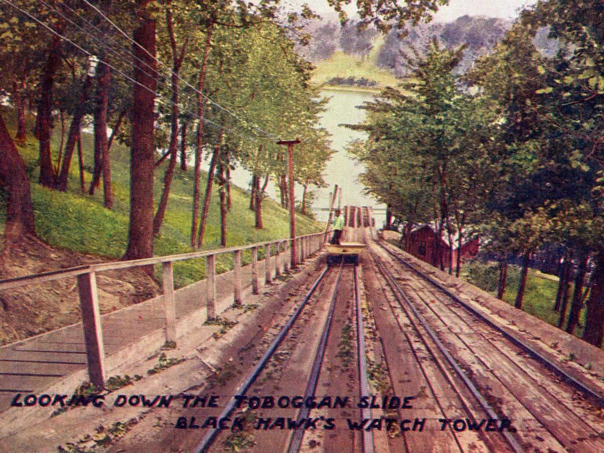 A vintage postcard of an amusement park ride on rails, amid trees