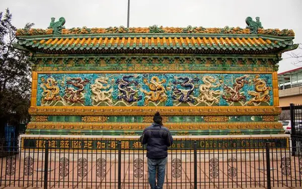 A person standing in front of the Nine Dragon Wall in Chinatown