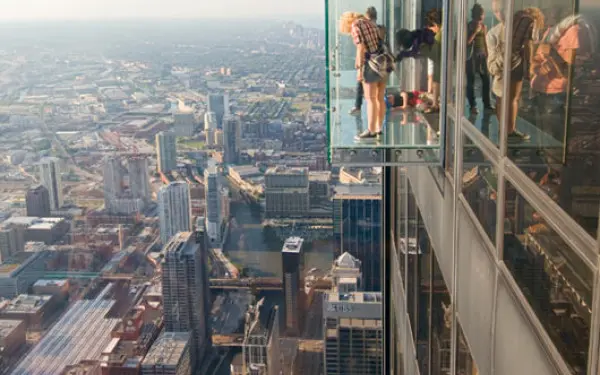 People standing in The Ledge, a glass box overlooking Chicago at Willis Tower
