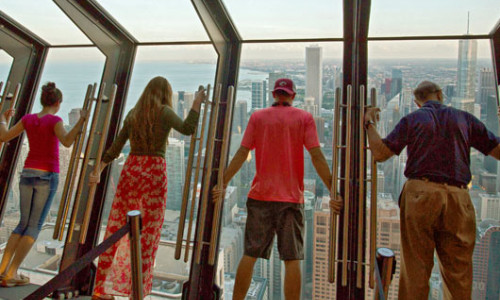 Four people leaning in the Tilt 360 attraction at the John Hancock Center.
