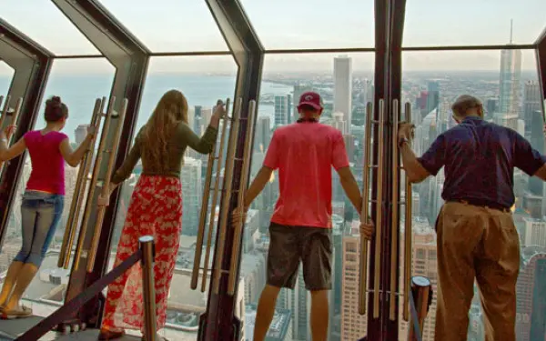 Four people leaning in the Tilt 360 attraction at the John Hancock Center.