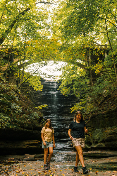 Two girls walk in front of a waterfall at Matthiessen State Park