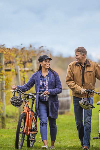 A couple walking with their bikes through the vines