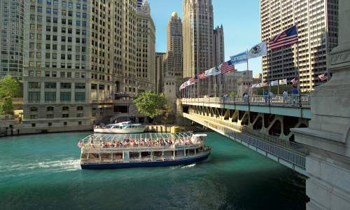 An architecture river tour boat passes under a bridge in Chicago