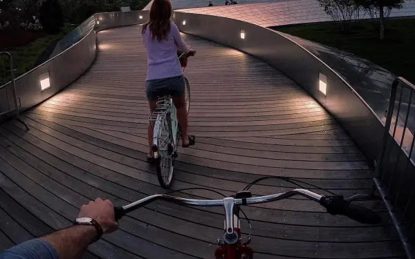 Two people biking down a bridge