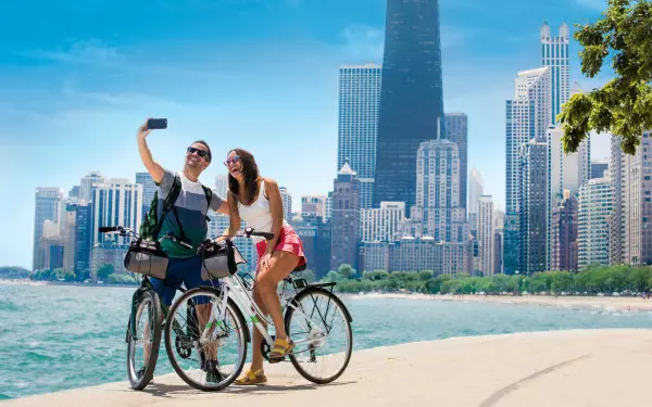 A couple biking along path beside lake and taking a photo