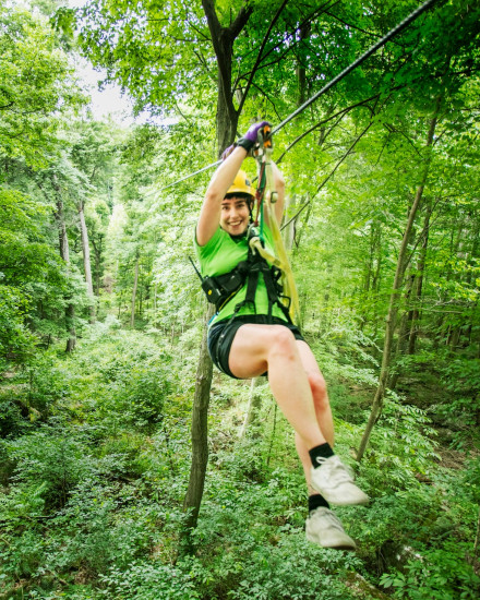 A woman sliding down a line from a flying fox amongst the trees
