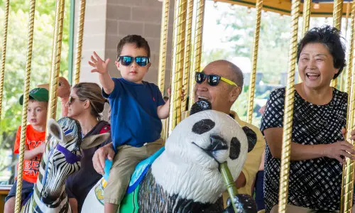A toddler and his grandparents on the carousel at the Brookfield Zoo.
