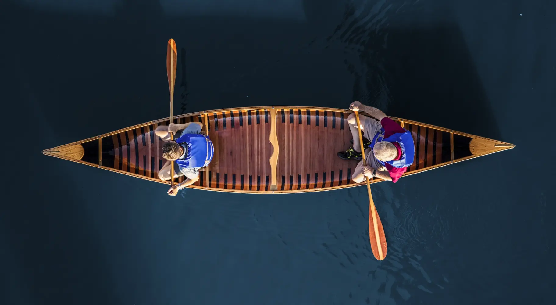 Aerial photo of two people in a canoe on blue water