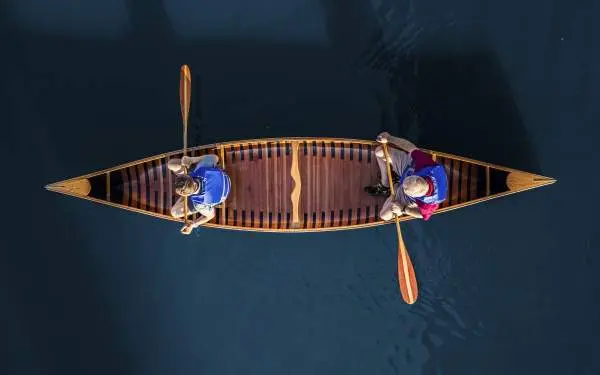 Aerial photo of two people in a canoe on blue water