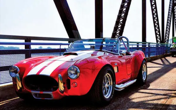 A red vintage car parked along the chain of rocks bridge
