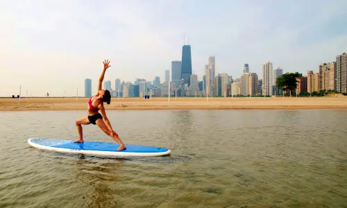 Lady stretching on paddle board on lake