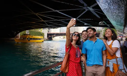 People posing for a photo by river under bridge 