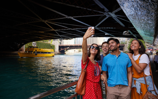People posing for a photo by river under bridge 
