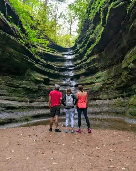 Three people staring up at a waterfall