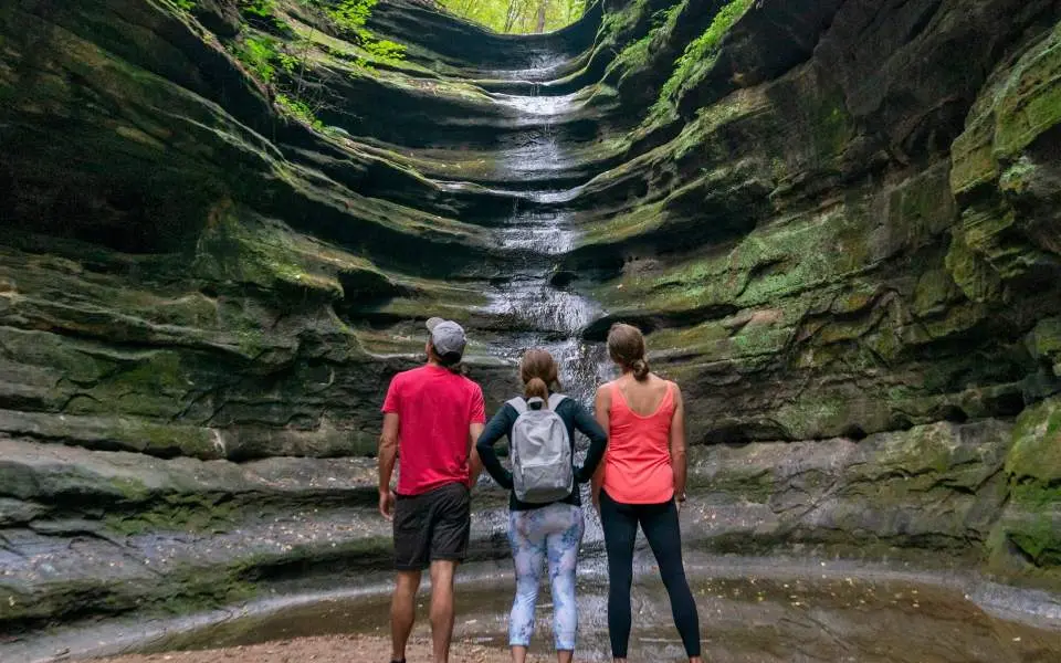 Three people staring up at a waterfall