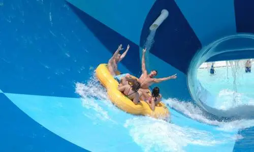 A group of four people in an inflatable raft on a water slide