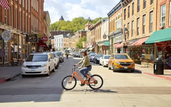 A cyclist on an e-bike crosses the main street of a small town